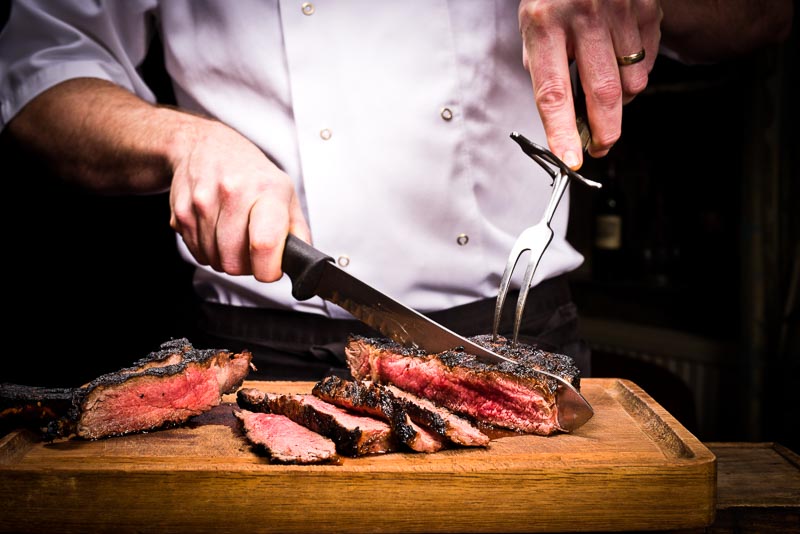 A magnificent steak being carved at the table.
